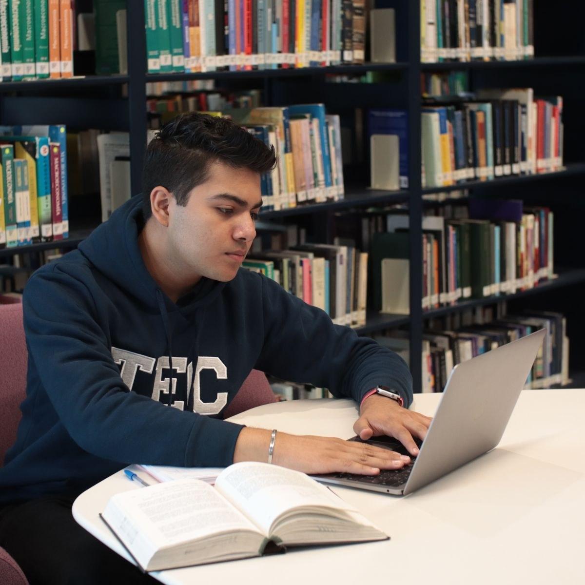 A student studying with a laptop and books in a library